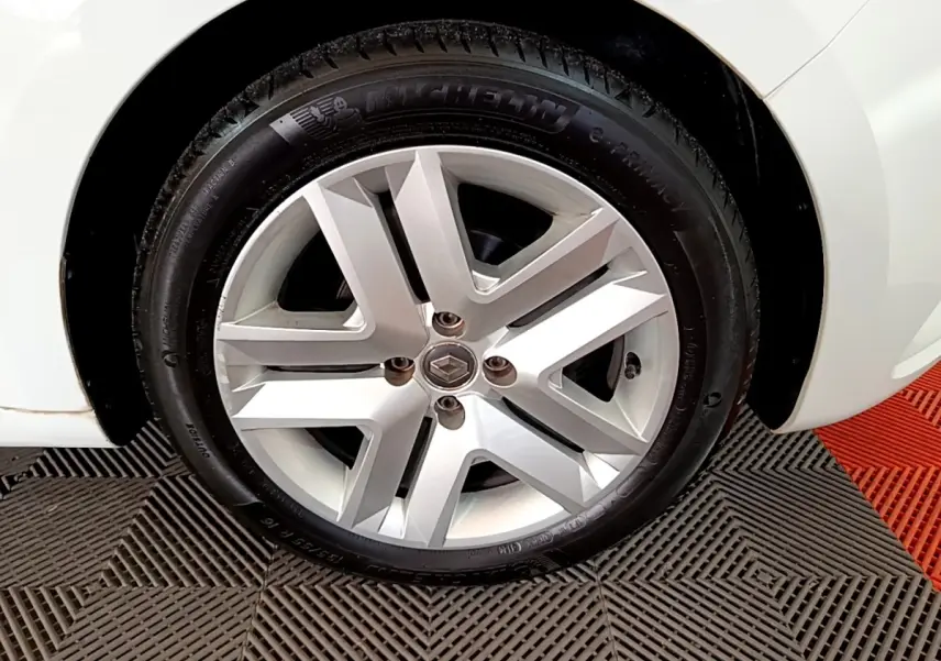 Gros plan sur la roue avant droite d'une Renault Clio blanche, mettant en valeur la jante alliage et le pneu Michelin.