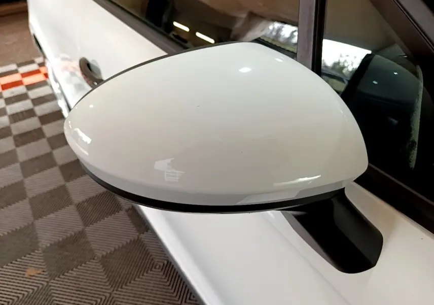 Gros plan sur le rétroviseur côté gauche blanc d'une Renault Clio Business 2021, avec portière et vitre visibles.