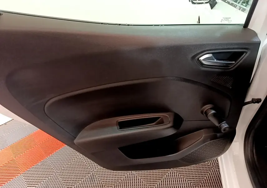 Vue rapprochée de la porte intérieure côté gauche noire d’une Renault Clio Business blanche, avec poignée de fenêtre manuelle.