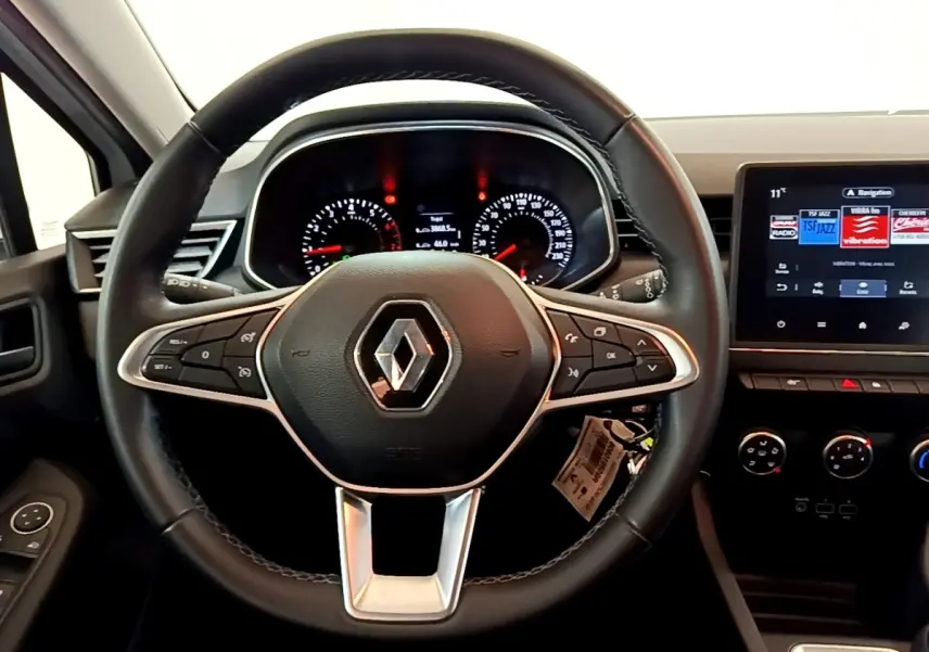 Vue rapprochée du volant cuir noir et du tableau de bord numérique de la Renault Clio Business blanche de 2021.