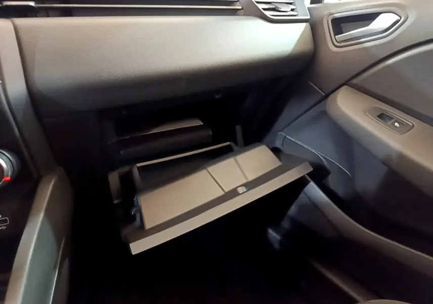 Intérieur de la Renault Clio Business blanche, vue côté passager avec boîte à gants ouverte et tableau de bord noir.