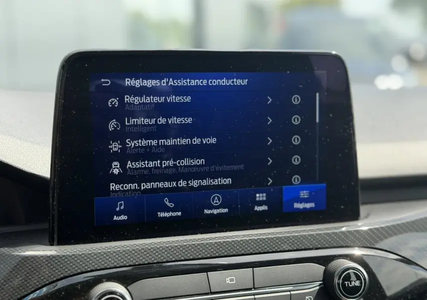 Écran tactile central du Ford Kuga 2024 affichant les réglages d’assistance conducteur, intérieur gris clair.