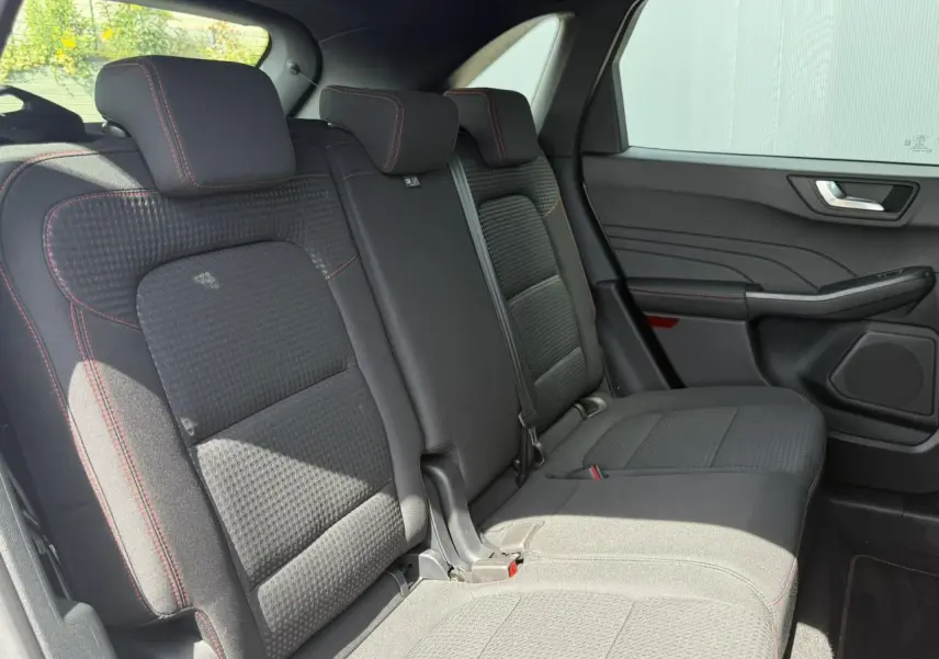 Vue latérale intérieure sur les sièges arrière noirs avec surpiqûres rouges du Ford Kuga 2024 finition ST-Line.
