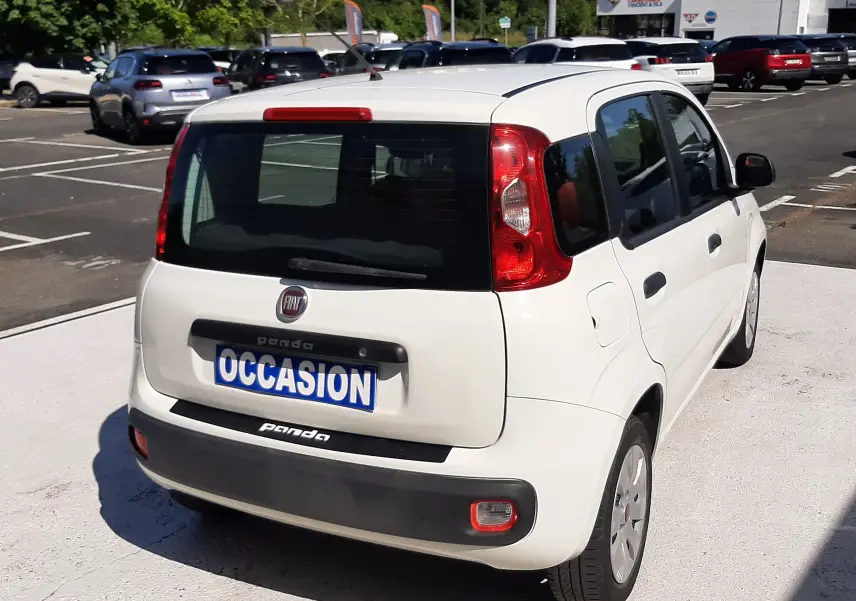 Vue 3/4 arrière droite d'une Fiat Panda blanche 2018 avec plaque "OCCASION" sur un parking extérieur.