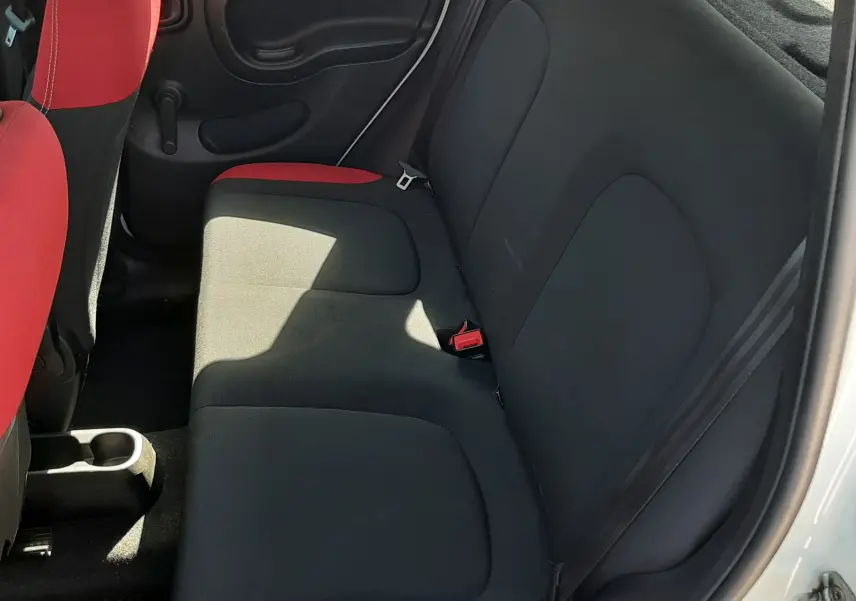 Vue intérieure arrière droite de la Fiat Panda 2018 avec sièges en tissu noir et rouge, portes blanches ouvertes.