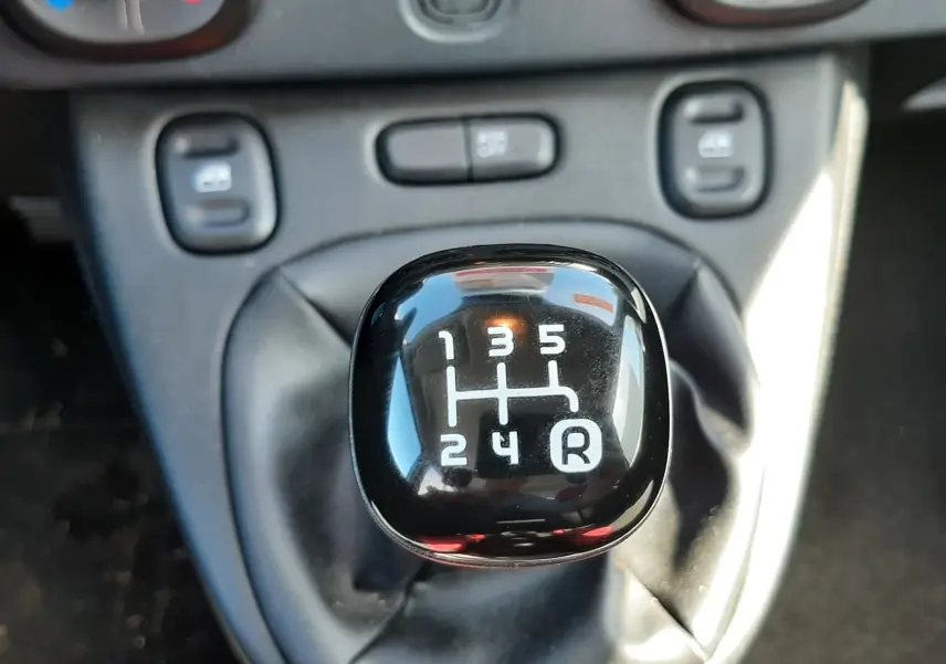 Gros plan sur le levier de vitesses manuel noir de la FIAT Panda blanche, avec console centrale en arrière-plan.