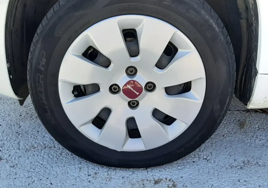 Gros plan sur la roue avant droite blanche d'une Fiat Panda 1.2 69CH POP de 2018 avec enjoliveur blanc et logo rouge.