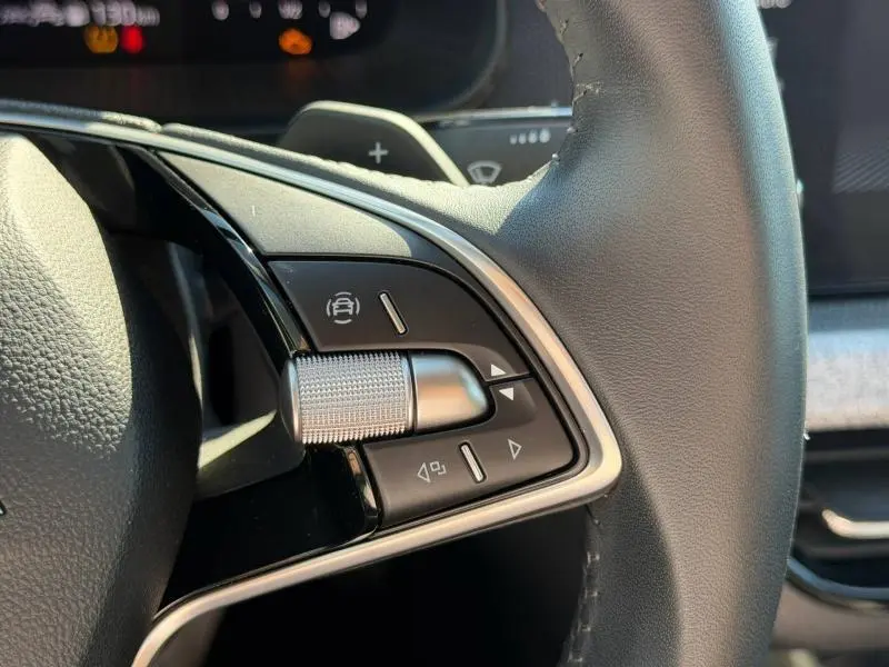 Gros plan sur les commandes multifonctions en aluminium brossé du volant cuir noir de la Skoda Scala 2025.