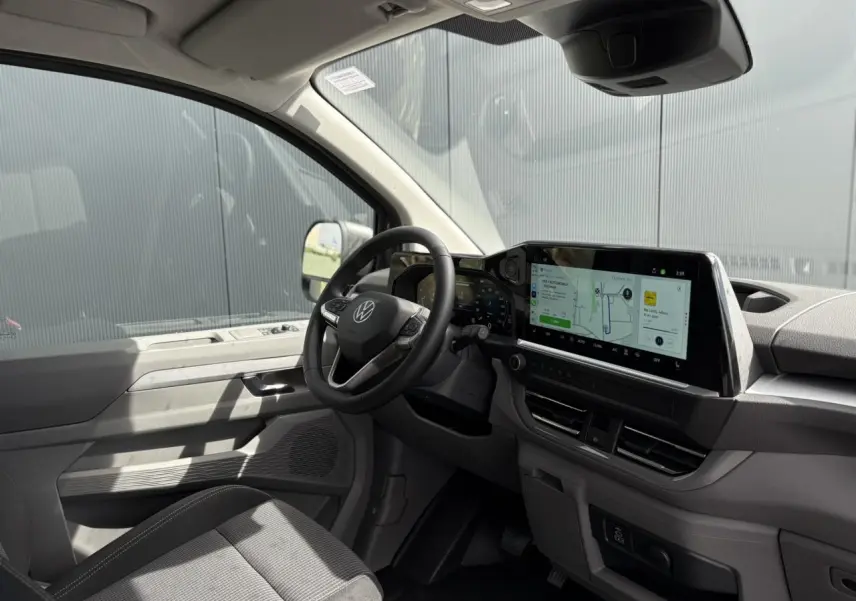Vue intérieure côté conducteur du Volkswagen Transporter T7 ProCab 2026, tableau de bord moderne avec écran tactile large.