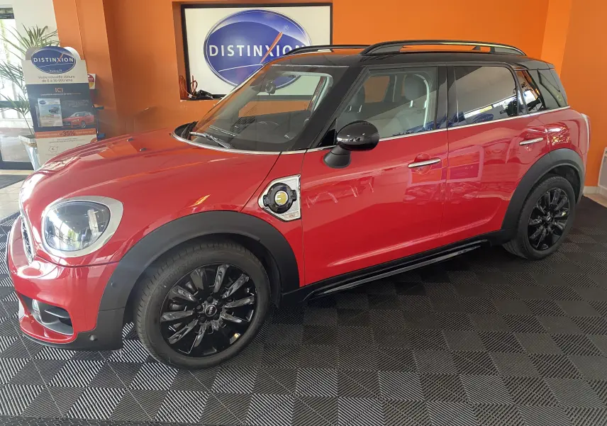 Vue de profil côté gauche d'une MINI Countryman Cooper SSE rouge avec toit noir et jantes noires en intérieur showroom.