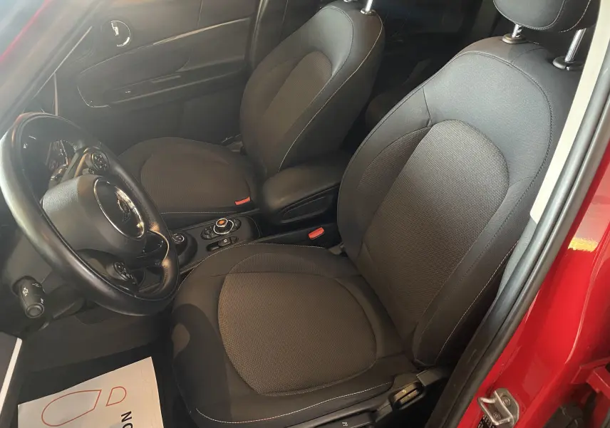 Vue intérieure côté conducteur du MINI Countryman rouge avec sièges en tissu noir et volant cuir multifonction.