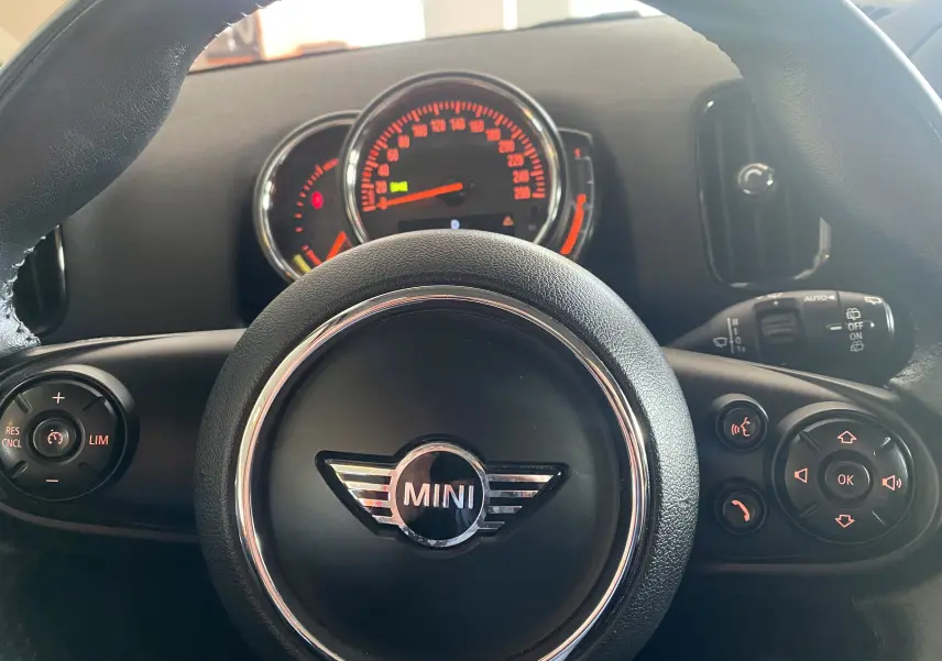 Vue rapprochée du volant en cuir noir avec logo MINI et tableau de bord éclairé en rouge du MINI Countryman 2018.