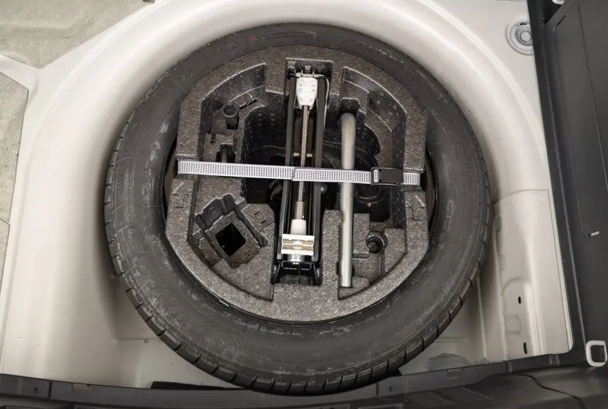 Roue de secours noire avec outillage intégré dans le coffre blanc cristallin d'une Skoda Fabia 2020 essence.