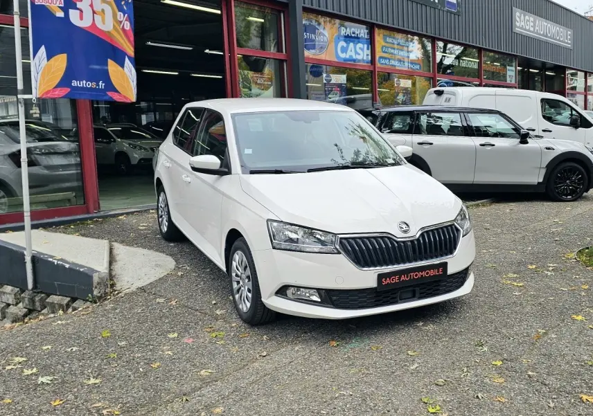 SKODA Fabia blanc cristal vue 3/4 avant garée devant un garage avec enseigne Sage Automobile.