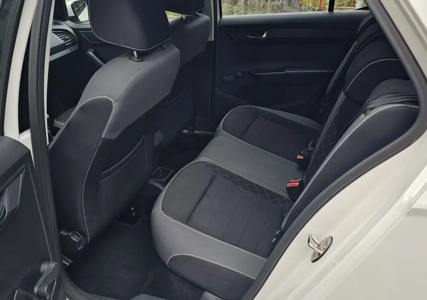 Vue côté gauche arrière de l'intérieur d'une Skoda Fabia 2020 blanc cristal, sièges noirs satin avec surpiqûres grises.