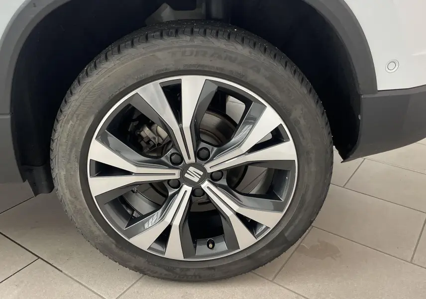 Gros plan sur la jante alliage 18'' usinée du côté arrière droit d'un SEAT Ateca blanc Nevada.