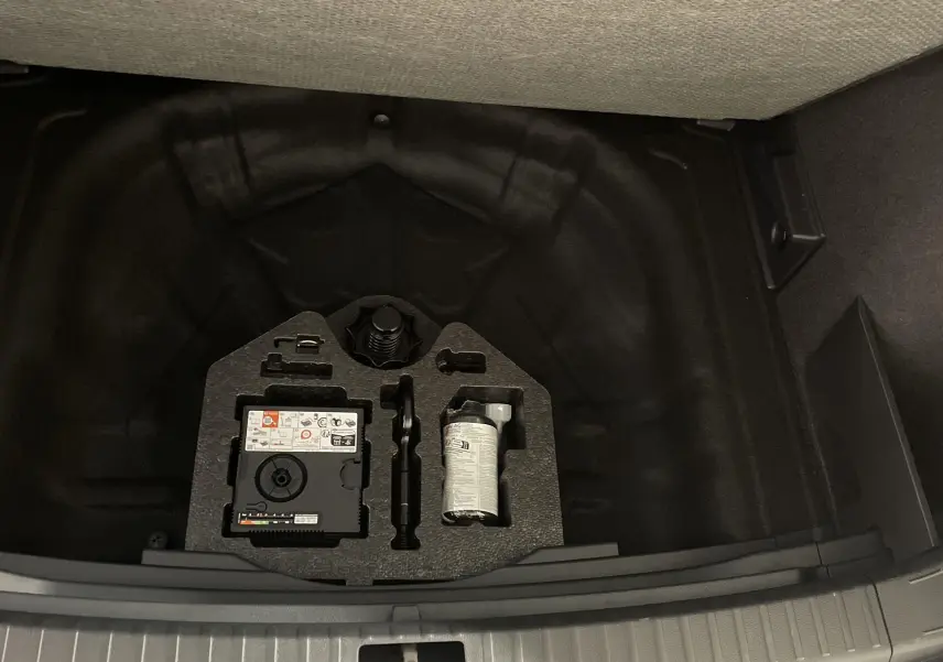 Coffre ouvert du SEAT Ateca blanc Nevada 2024, vue sur le rangement sous plancher avec kit de réparation pneus.