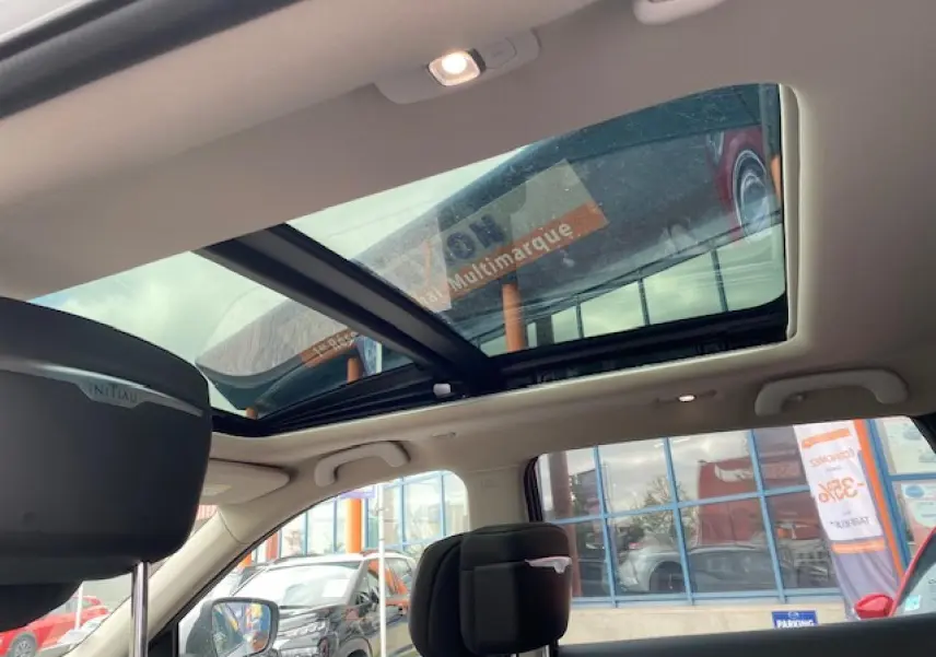 Toit panoramique ouvert sur l'intérieur d'un Renault Koleos blanc 2019, vue côté gauche avec appuie-tête Initiale Paris.