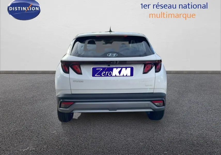 Vue arrière d'un Hyundai Tucson blanc Atlas 2026 avec feux arrière LED et plaque Zéro KM visible.