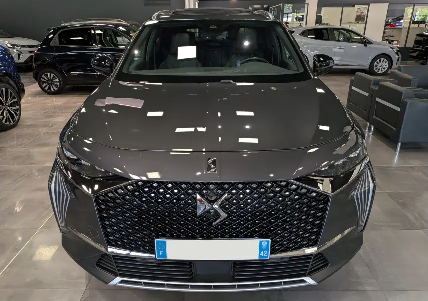 Vue avant d’un DS7 BlueHDi gris 2024 avec calandre distinctive et éclairage LED en showroom.