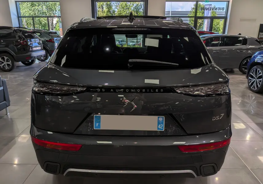 Vue arrière d'un DS7 gris 2024 dans un showroom, avec feux arrière étirés et logo DS centré sur le hayon.