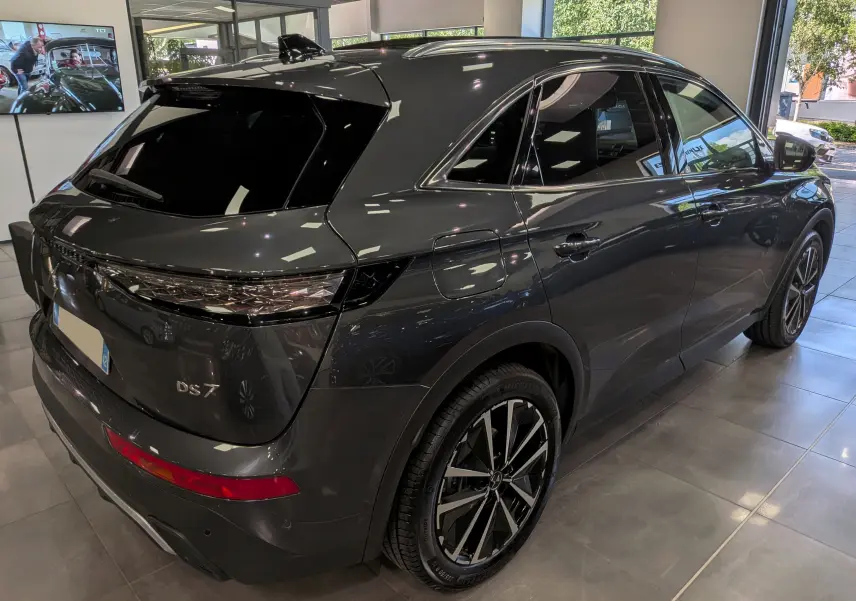 Vue 3/4 arrière droite du SUV DS7 BlueHDi gris foncé, avec jantes bi-ton et vitres teintées en showroom.