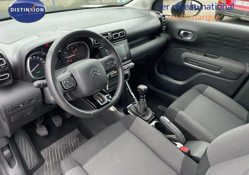 Vue intérieure côté conducteur du Citroën C3 Aircross gris platinium, montrant le tableau de bord et la boîte manuelle.