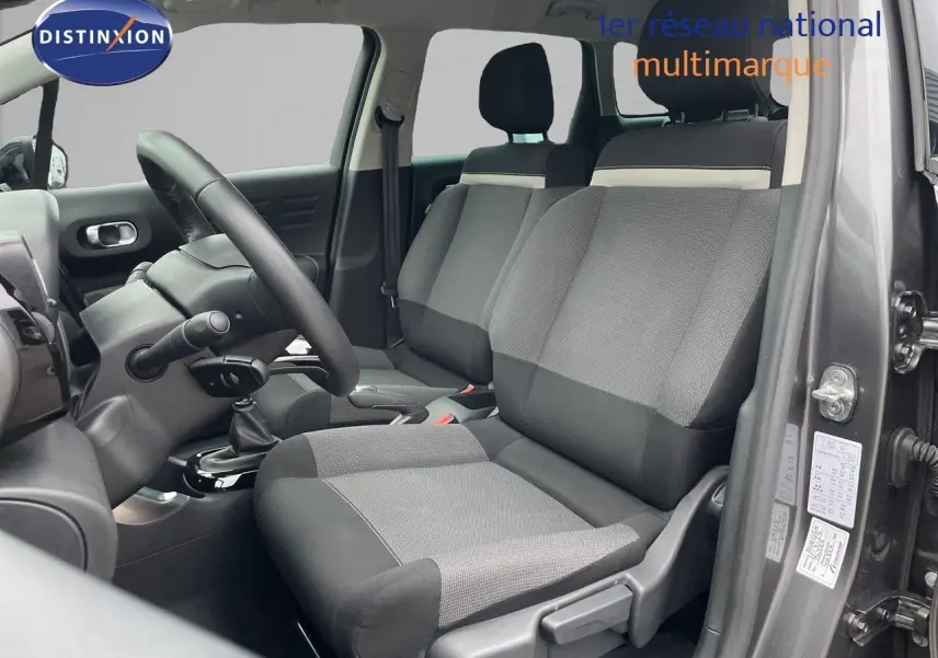 Vue intérieure côté conducteur du Citroën C3 Aircross gris platinium, montrant les sièges en tissu gris et noir.