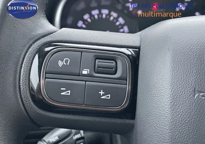 Gros plan sur les commandes de volume et téléphone intégrées au volant du Citroën C3 Aircross gris platinium 2023.