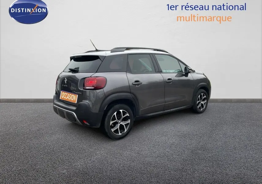 Vue 3/4 arrière droite d'une Citroën C3 Aircross gris platinium métal avec jantes bi-ton et toit noir.