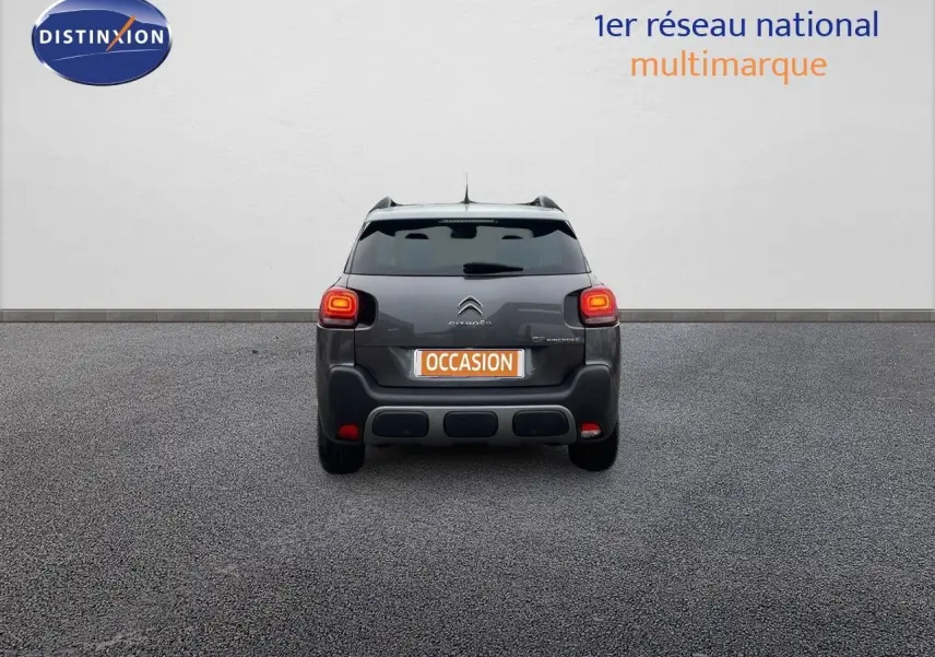 Vue arrière d'un Citroën C3 Aircross gris platinium métal avec feux allumés sur fond neutre.