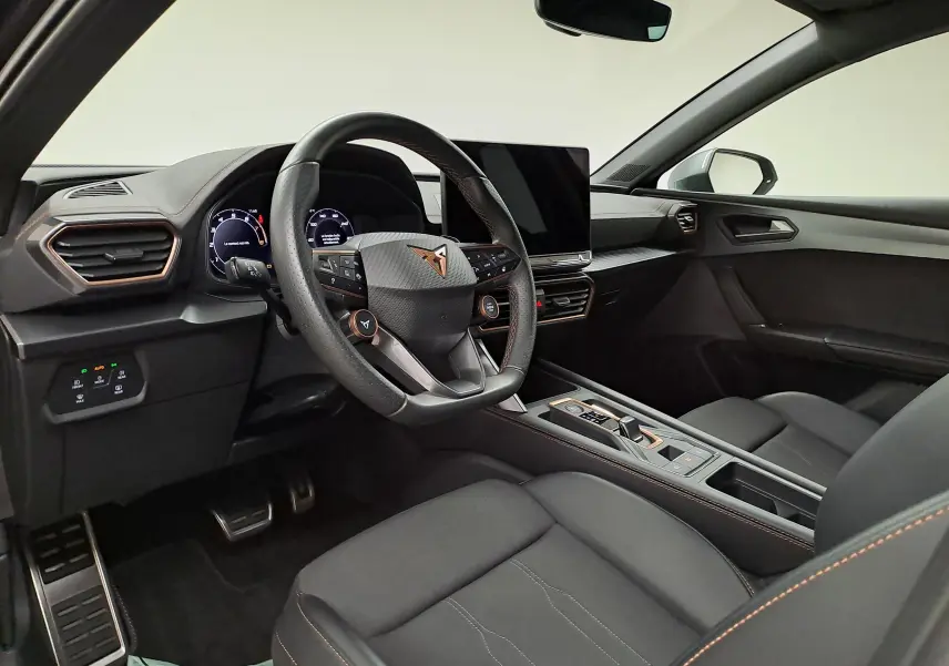 Intérieur avant droit de la CUPRA Leon Ph.2 noir minuit, volant multifonction et écran central tactile moderne.