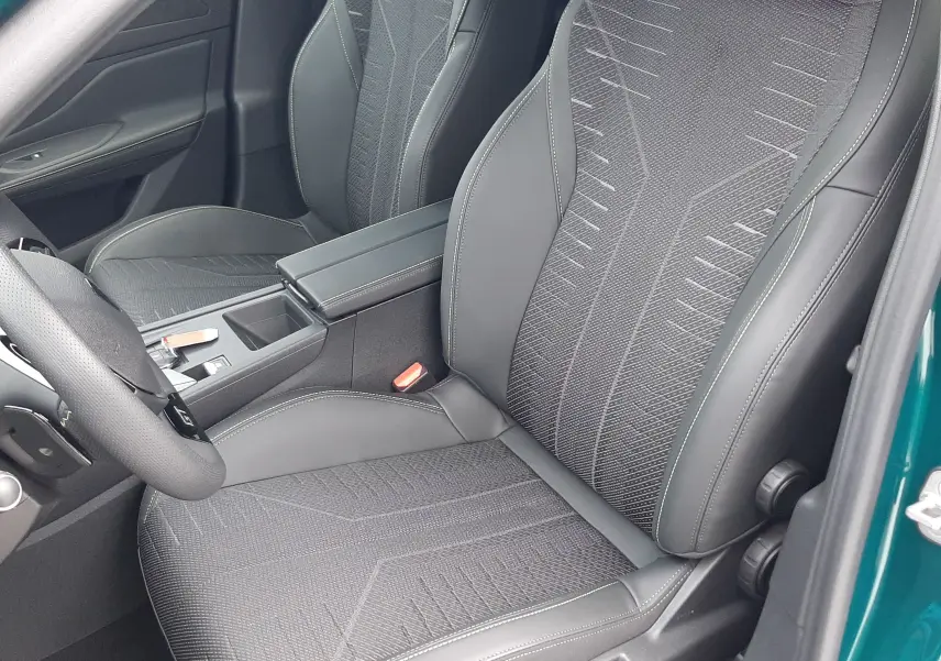 Vue intérieure côté conducteur de la Peugeot 308 1.2 Hybrid 145ch GT bleu Lagoa, sièges en tissu et cuir noir avec surpiqûres.