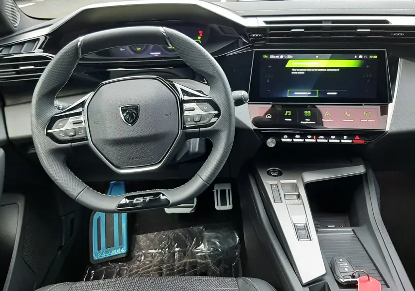 Vue intérieure frontale du poste de conduite de la Peugeot 308 GT hybride, avec volant compact et écran tactile central.