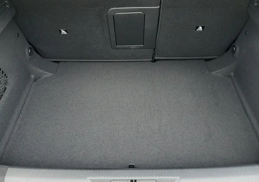 Coffre ouvert vu de dessus de la Peugeot 308 1.2 Hybrid 145ch GT Bleu Lagoa, intérieur noir et tapis plat.