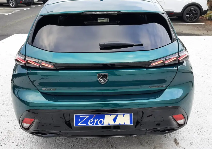 Vue arrière d'une Peugeot 308 hybride bleu Lagoa avec feux LED distinctifs et plaque Zéro KM.