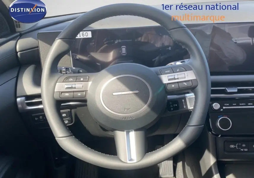 Vue intérieure centrée sur le volant cuir multifonction du Hyundai Tucson gris Ecotronic, avec tableau de bord digital.