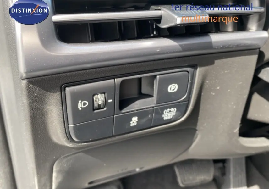 Gros plan sur les commandes de réglage des phares et frein de stationnement du Hyundai Tucson gris Ecotronic 2026.