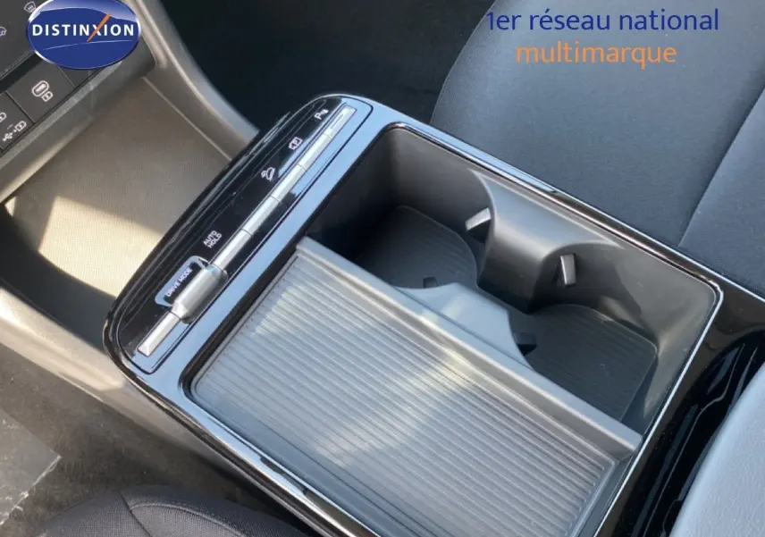 Vue rapprochée de la console centrale du Hyundai Tucson gris Ecotronic, avec porte-gobelets et commandes tactiles.