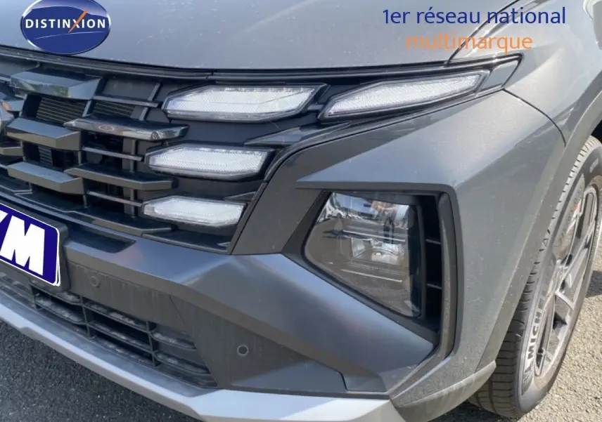 Gros plan sur l'avant droit du Hyundai Tucson gris Ecotronic Metal, mettant en valeur la calandre et les phares LED distinctifs.