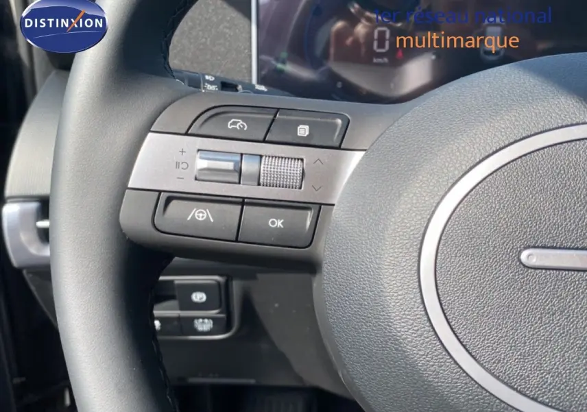 Gros plan sur le volant multifonction noir du Hyundai Tucson 2026, avec commandes intégrées et tableau de bord numérique flou.