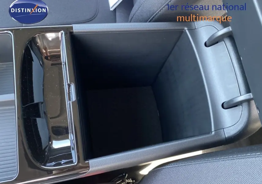 Vue en plongée sur le rangement central ouvert du Hyundai Tucson gris Ecotronic Metal, intérieur tissu noir visible.