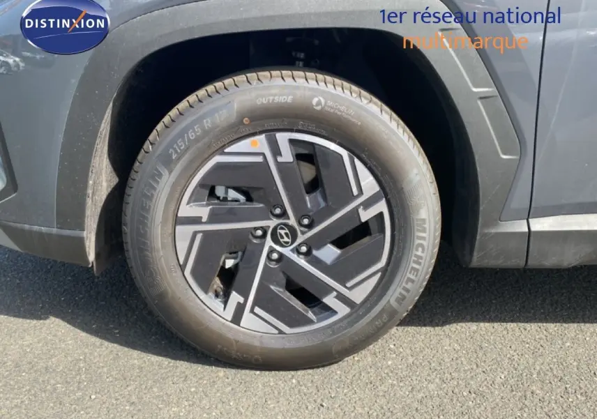 Gros plan sur la roue avant gauche du Hyundai Tucson gris Ecotronic Metal avec jante alliage noire et grise.