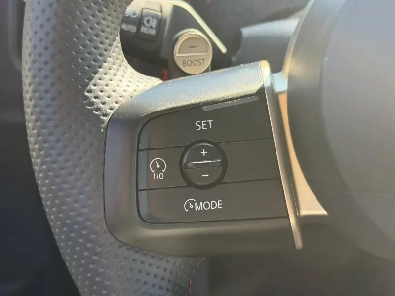 Gros plan sur les commandes du volant perforé de la MINI Countryman C 170ch JCW argentée, bouton Boost visible.