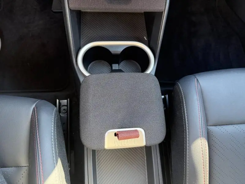 Vue plongeante sur l'accoudoir central en tissu gris et porte-gobelets du MINI Countryman argenté 2025, finition JCW.