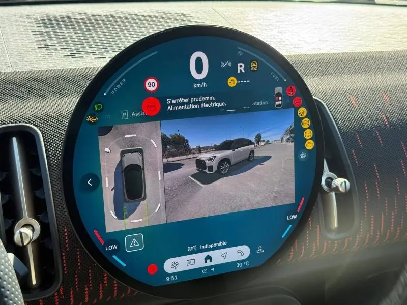Écran tactile central montrant la vue 360° et la caméra arrière d'une MINI Countryman argentée en stationnement.