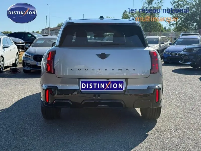 Vue arrière d'un MINI Countryman argenté 2025 avec feux arrière LED et logo central noir sur un parking.