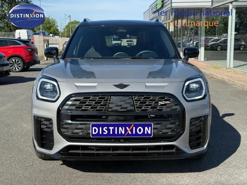 Vue avant d'une MINI Countryman JCW argentée avec calandre noire et bandes décoratives sur le capot.