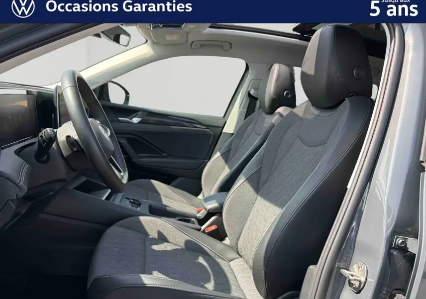 Intérieur avant du Volkswagen Tiguan gris 2025, vue côté droit sur les sièges tissu et cuir avec toit panoramique ouvert.