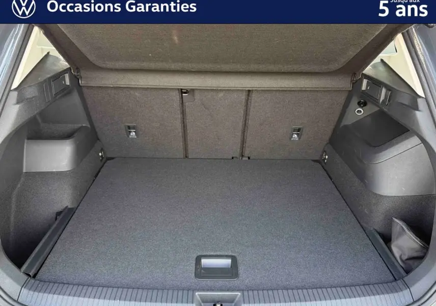 Coffre ouvert vu de l'arrière d'un Volkswagen Tiguan gris, montrant un espace de chargement propre et spacieux.